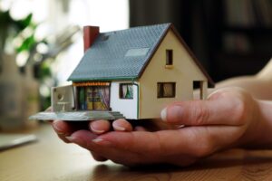 Closeup of a miniature house in a female hand - Real estate concept