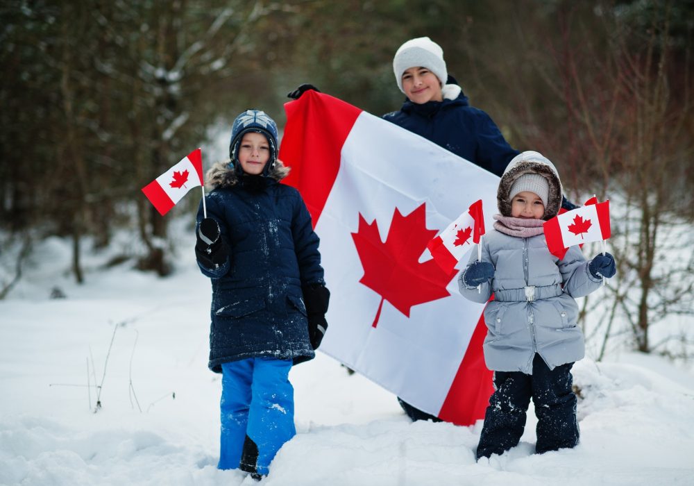 Childrens holding flag of Canada on winter landscape.